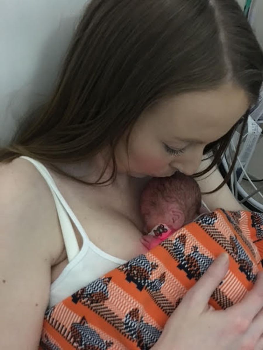 Premature newborn baby receiving skin-to-skin contact with mother in hospital, wrapped in blanket